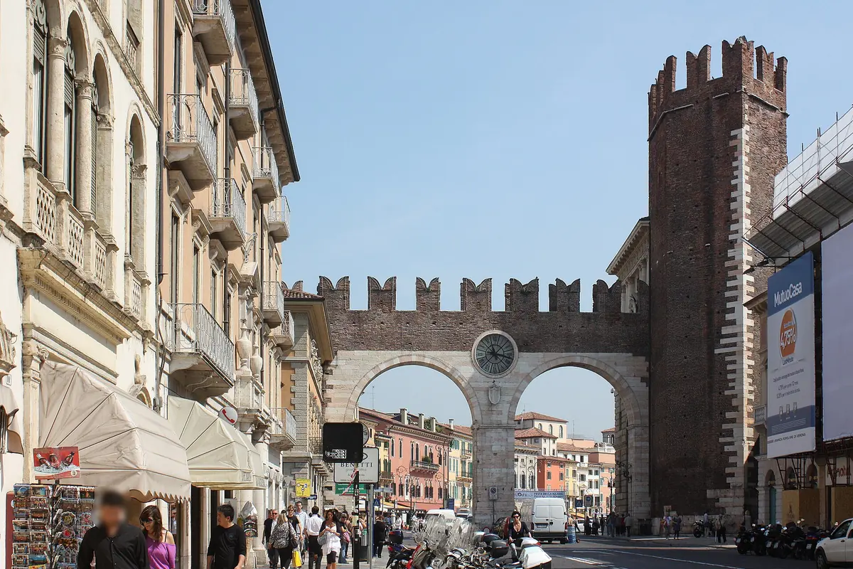 The Portoni della Bra, a crenellated city gate with two arches and a clock between them